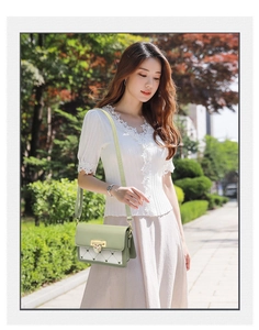Detail of light green flap crossbody bag featuring a golden heart buckle and quilted pattern