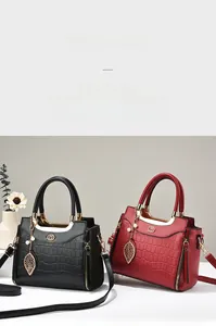 Detail of crocodile pattern leather handbag with gold hardware and leaf pendant charm