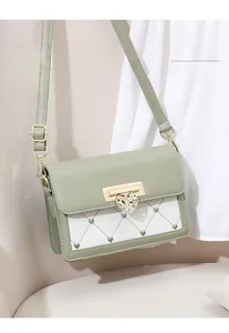Close-up of small crossbody bag featuring a green floral heart-shaped lock and quilted texture