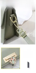 Detail of the green leather bag showing the golden heart floral buckle and adjustable strap
