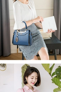 Detail of blue crocodile pattern PU leather handbag with gold leaf charm and metal logo