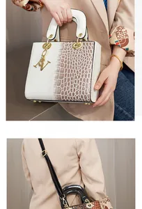 Detail der Handtasche aus Leder mit Krokodilprägung, weißen Griffen und SV-Anhängern