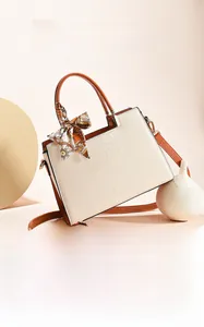 Detail view of beige crocodile embossed leather handbag with brown trim and silk scarf