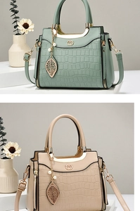 Detail of elegant crocodile-pattern leather handbags with metal handles and leaf charms