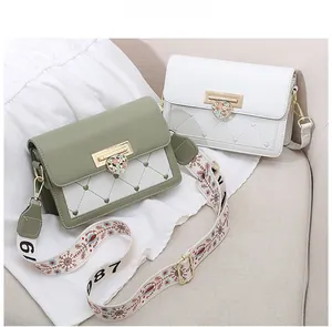 Detail of square crossbody bags with heart-shaped metal buckles and embroidered wide straps
