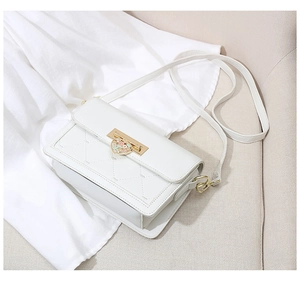 Detail of the white quilted crossbody bag featuring a colorful heart-shaped metal buckle