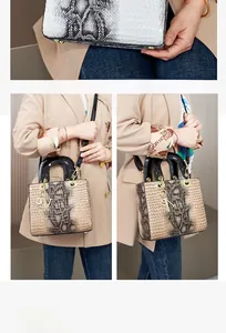Detail einer beigen Handtasche mit Krokodilmuster, schwarzen Griffen und Goldanhänger