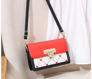 Detail of red heart embroidery and floral gold metal lock on tricolor small square bag