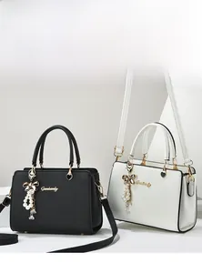 Détail de sacs à main noir et blanc avec logo doré et pendentif perle élégant