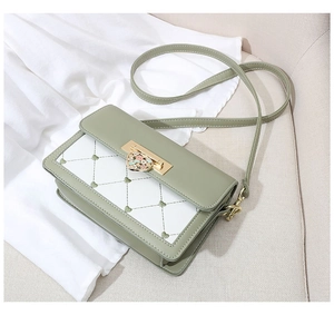 Detail of sage green crossbody bag with white heart-quilted panel and gold floral clasp