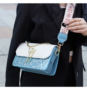 Detail of blue sequin handbag with pearl cat pendant and ethnic style wide shoulder strap