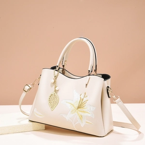 Elegant cream embroidered handbag with lily floral patterns and pearl leaf charm