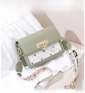 Close-up of heart-stitched flap bag with floral charm and embroidered wide shoulder strap