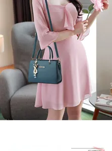 Détail du sac en cuir sarcelle avec logo doré et accessoire de nœud en perles