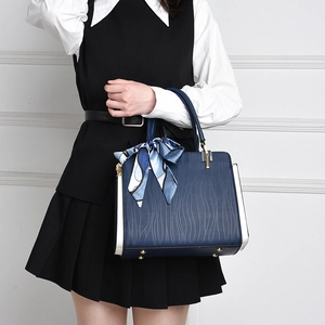 Detail of dark blue handbag with white side panels and elegant scarf wrap on handle