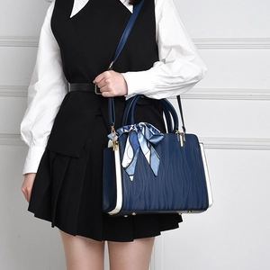Close-up of deep blue leather handbag with wave pattern and decorative silk scarf