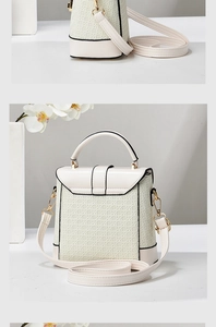 Detail of cream woven leather handbag with black contrast trim and golden metal clasps