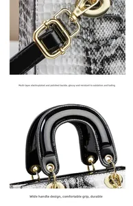 Details einer Handtasche mit Schlangenhaut-Textur, goldener Hardware und schwarzem Griff
