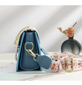 Detail of blue and white crossbody bag with ethnic embroidered strap and gold chain