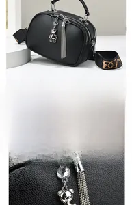 Detail of black lychee grain leather bag with silver bear charm and tassel ornament