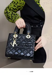 Detail of black patent leather handbag with quilted diamond pattern and gold hardware