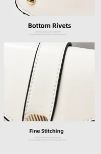 Detail view of gold bottom rivets and delicate stitching on a white leather handbag