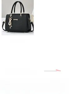 Détail d'un sac à main en cuir noir avec breloque perle et logo métallique chic