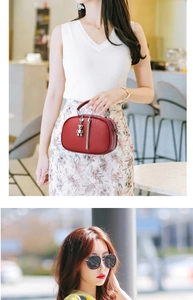 Detail of red pebbled leather handbag featuring metal round handle and silver bear charm