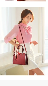 Detail of red embossed leather handbag with floral scarf and golden metal hardware