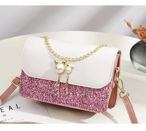 Macro view of macaron pink glitter crossbody bag with gold chains and cat pearl charms