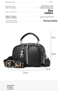 Detailed view of black pebble leather handbag with silver bear charm and floral wide strap