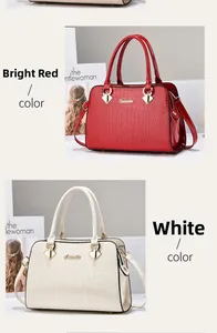 Detail der Handtasche mit Steinstruktur, goldenem Logo in Rot und Cremeweiß-Tönen