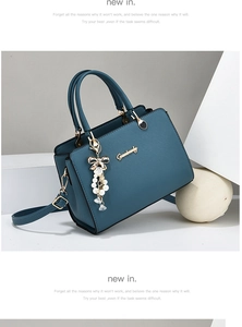 Détail du sac en similicuir bleu avec logo doré, pendentif perle et bandoulière