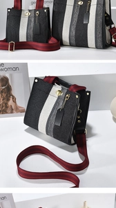 Close-up of striped canvas tote with gold twist lock and maroon woven shoulder straps
