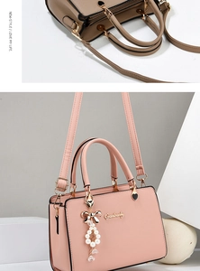 Détail de la texture cuir grainé avec logo doré et pompon perlé sur un sac à main chic