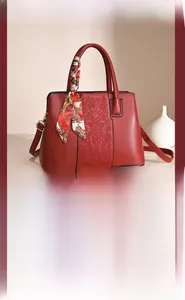 Close-up of red embroidered wedding handbag with decorative silk scarf on handle