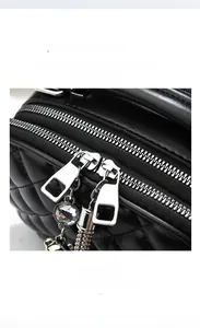 Detail of dual metal zippers with rhinestone bear charm and chain tassel on quilted bag