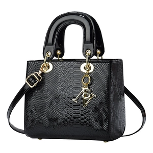Klassische schwarze Lackleder-Handtasche mit Schlangenmuster und goldenen Metallanhängern