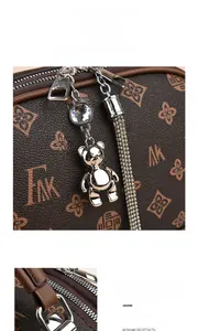 Gros plan du sac à main monogramme marron avec breloque ours argentée et pompon strass