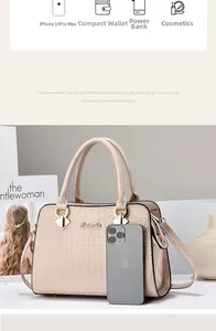 Detail der beigen Handtasche mit Krokodilmuster, Metalllogo und geräumigem Innenraum