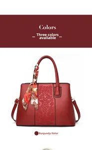 Detail view of burgundy handbag with floral embroidery and decorative floral silk scarf