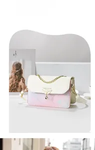 Détail du sac bandoulière floral avec boucle aile dorée et poignée en chaîne métal