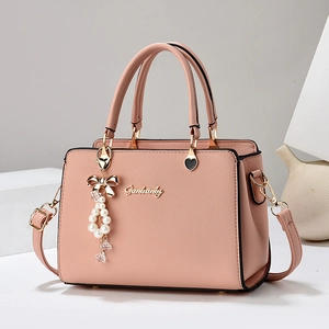 Sac à main bandoulière rose texturé élégant avec breloque perle et poignées sur fond épuré