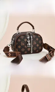 Détail du sac bandoulière marron monogrammé avec large sangle et breloque ours