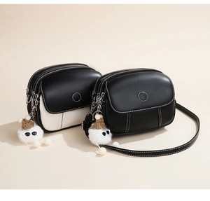 Detailed view of women's shoulder bags with white contrast stitching and cute pompom charm