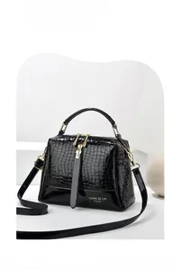 Nahaufnahme der schwarzen Lackledertasche mit Krokoprägung und goldenem Reißverschluss