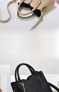 Detail von Lederhandtaschen in Beige und Schwarz mit vertikaler Textur und Goldkette