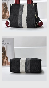 Detailed view of woven tote with striped pattern and red checkered handles with gold rivets