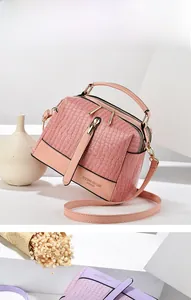 Detail der rosa Handtasche mit Krokodilprägung, Lackleder-Struktur und verstellbarem Riemen