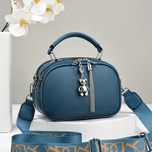 Dark blue pebbled leather handbag with bear charm and patterned wide shoulder strap